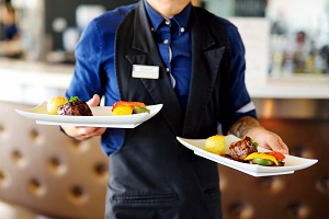 Waiter carrying two plates with meat dish on some festive event, party, wedding reception or catered event