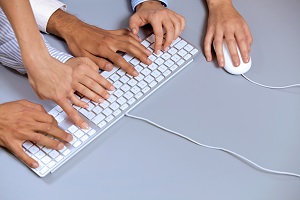 Human hands on computer keyboard with one hand using computer mouse