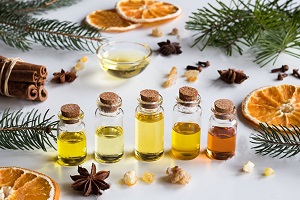 Christmas selection of essential oils and spices on white background: bottles of essential oil, spruce, fir, frankincense resin, star anise, cinnamon, clove, dried orange.